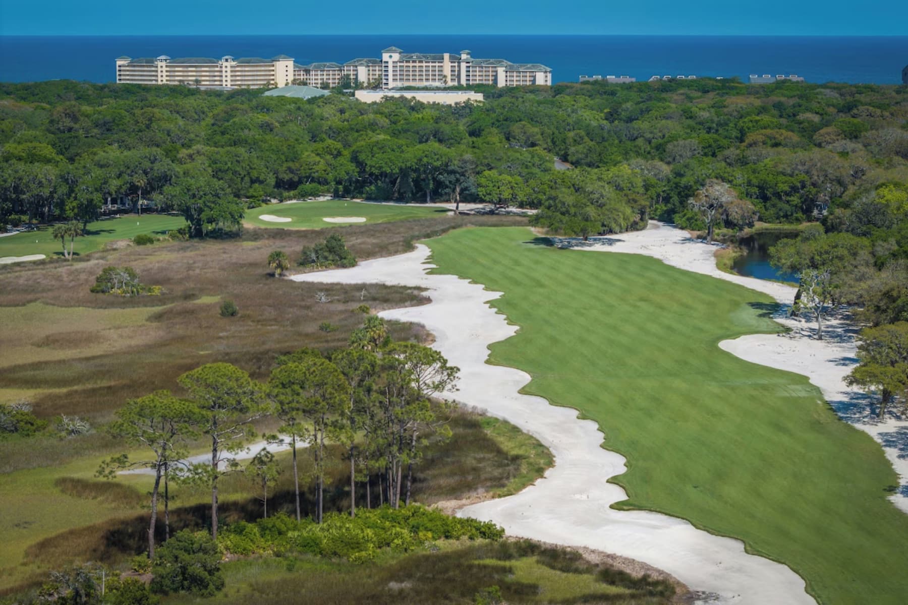 A Long Point fairway edged by waste bunkers and marsh, the resort and ocean beyond