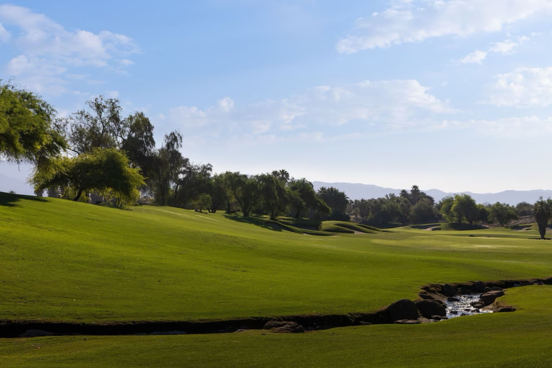 A natural desert wash cuts across a rolling Mountain View fairway