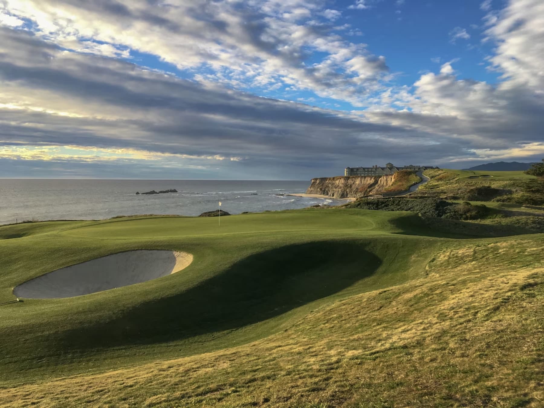 A bluff-top green on the Ocean Course, the Ritz-Carlton on the point beyond.